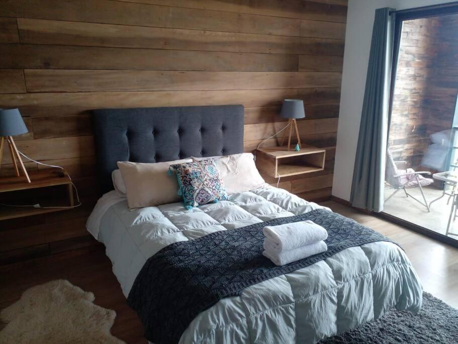 a bedroom with a large bed with a blue headboard at Acogedor en parcela in Llanquihue