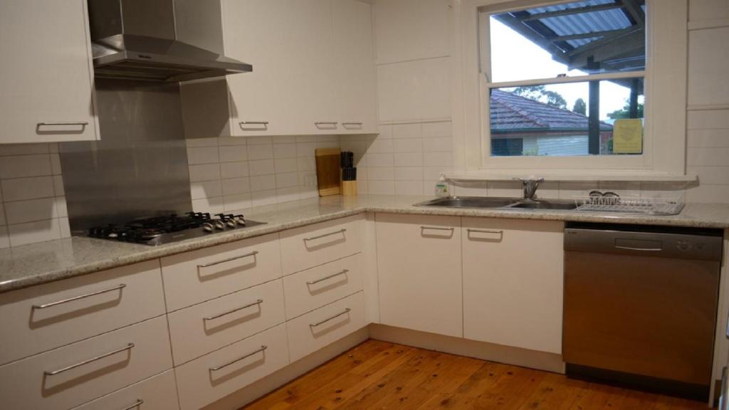 a kitchen with white cabinets and a sink and a window at Coolamon on Marsh in Armidale