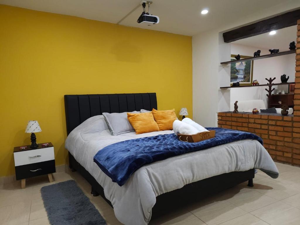 1 dormitorio con 1 cama con manta azul y almohadas de color naranja en Samor centro histórico Bogota en Bogotá