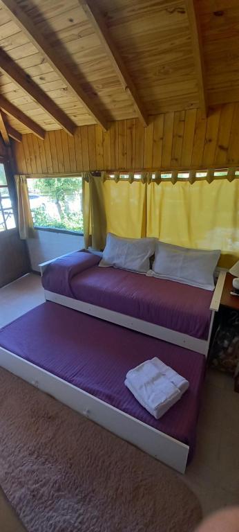 a bedroom with two beds with purple sheets and yellow curtains at Departamento Anita in El Hoyo