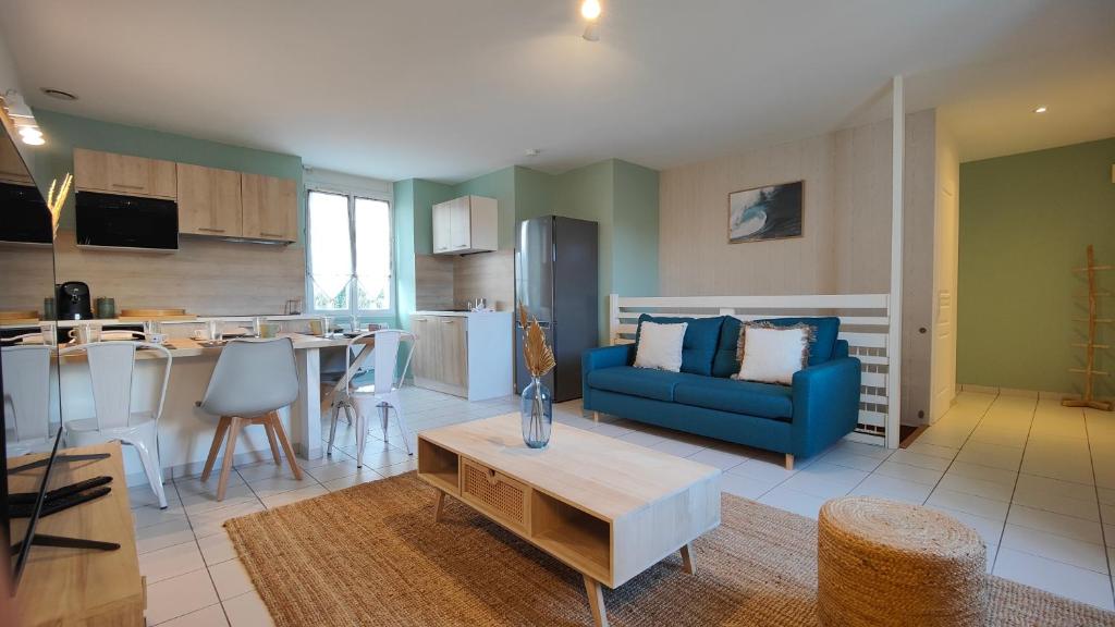 een woonkamer met een blauwe bank en een keuken bij Appartement centre-ville proche lac, océan, vignes in Lesparre-Médoc