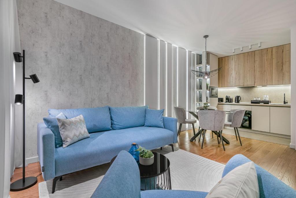 a living room with a blue couch and a kitchen at Melody Apartment in Novi Beograd