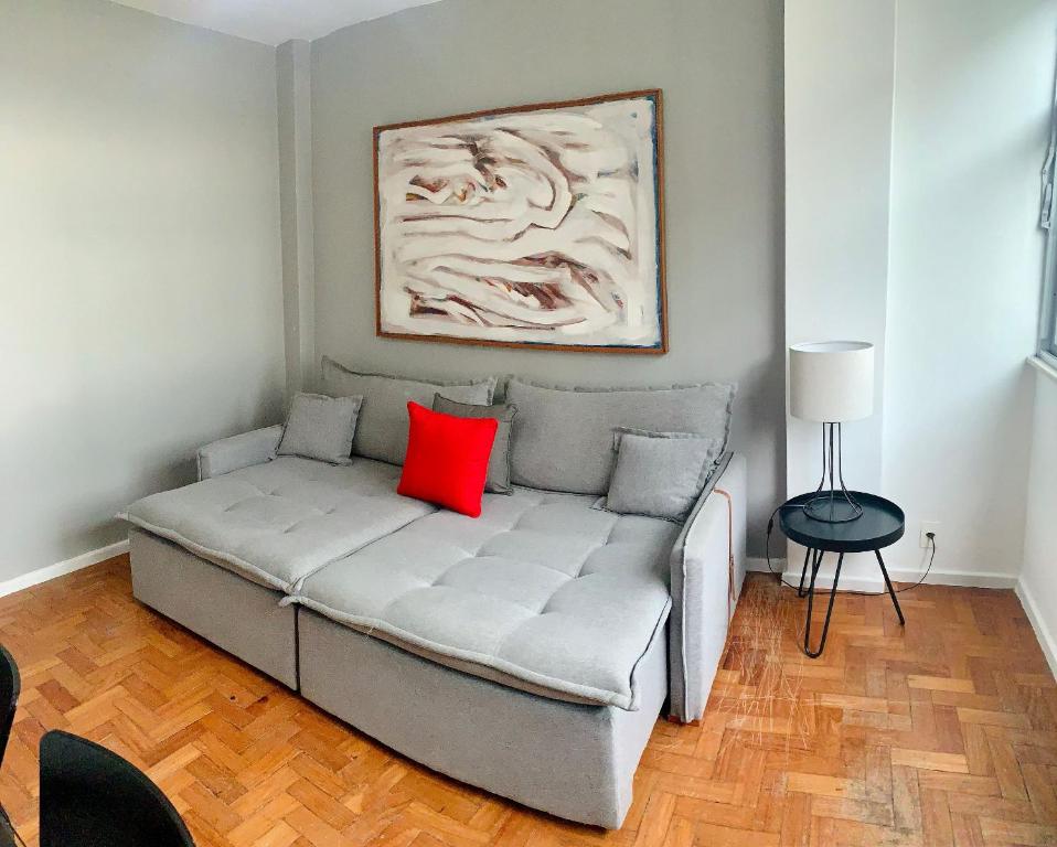 a couch with a red pillow on it in a room at Fronteira Leblon/Ipanema - Vista fantástica! in Rio de Janeiro