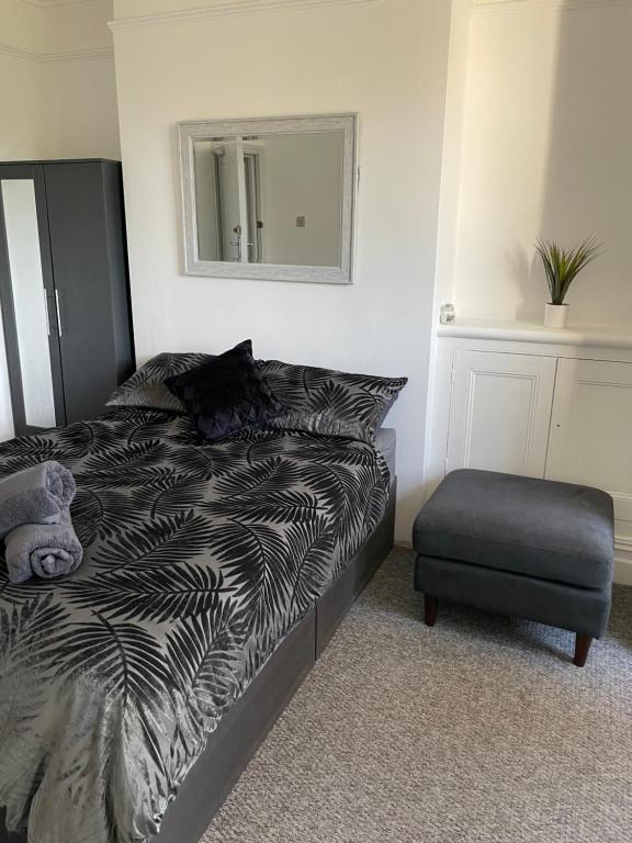 a bedroom with a bed and a chair and a mirror at Tiye cosy stays in Stoke on Trent