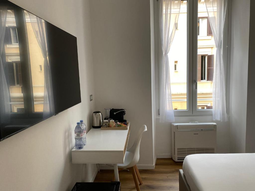 a white room with a bed and a desk and window at Belltower Elegans in Rome