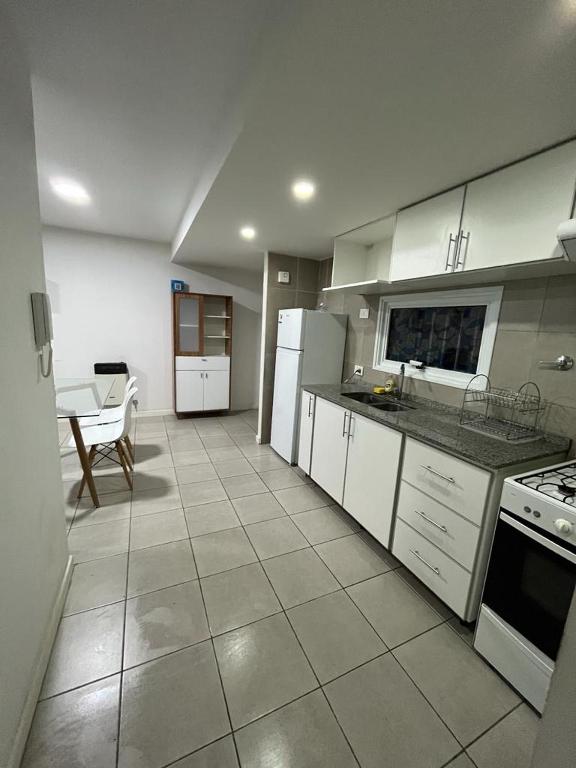 a large kitchen with white appliances and a table at Departamento centrico in La Cieneguita