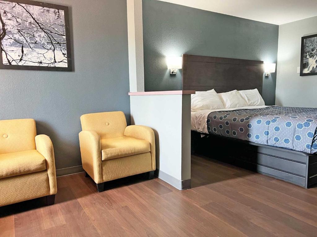 a hotel room with a bed and two chairs at Red Carpet Inn & Suites in Newnan