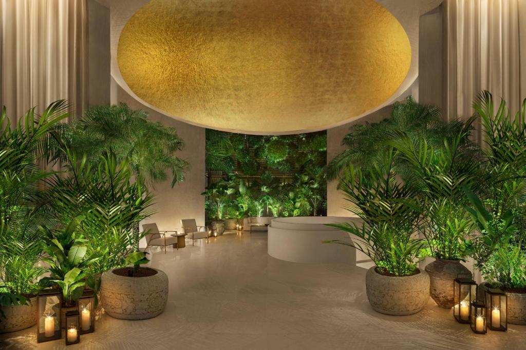 a lobby with potted plants and a large gold ceiling at The Singapore EDITION in Singapore