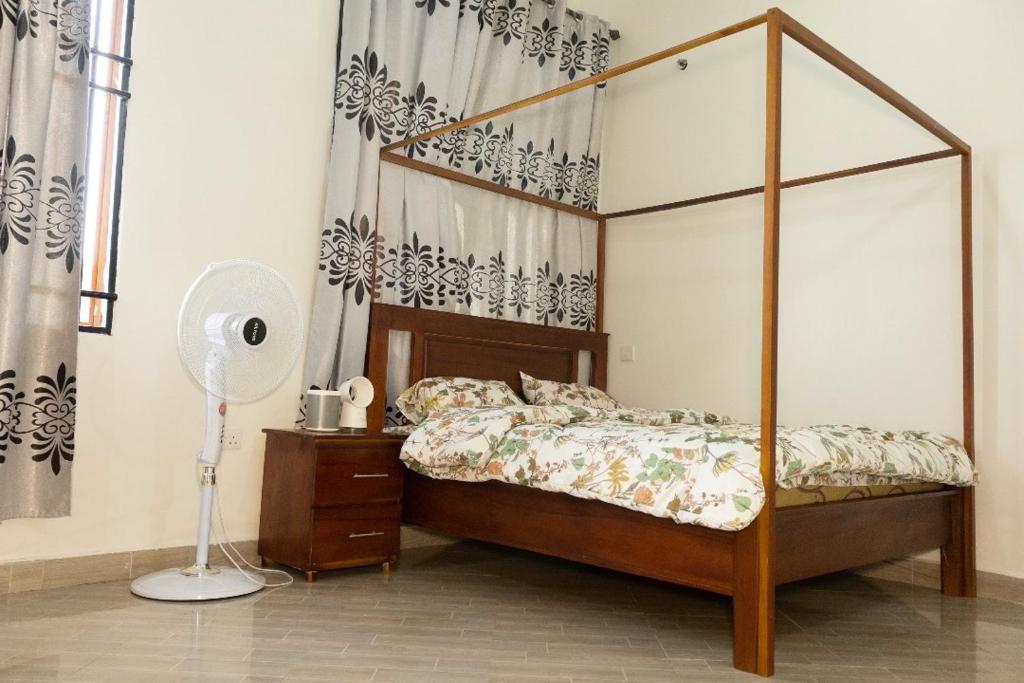 1 dormitorio con cama con dosel y ventilador en Morris Multi en Dar es Salaam