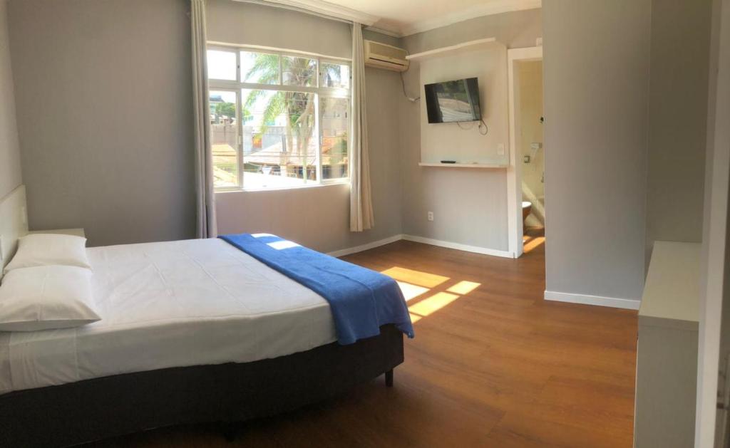 1 dormitorio con cama y ventana grande en MONTE LÍBANO HOTEL II, en Florianópolis