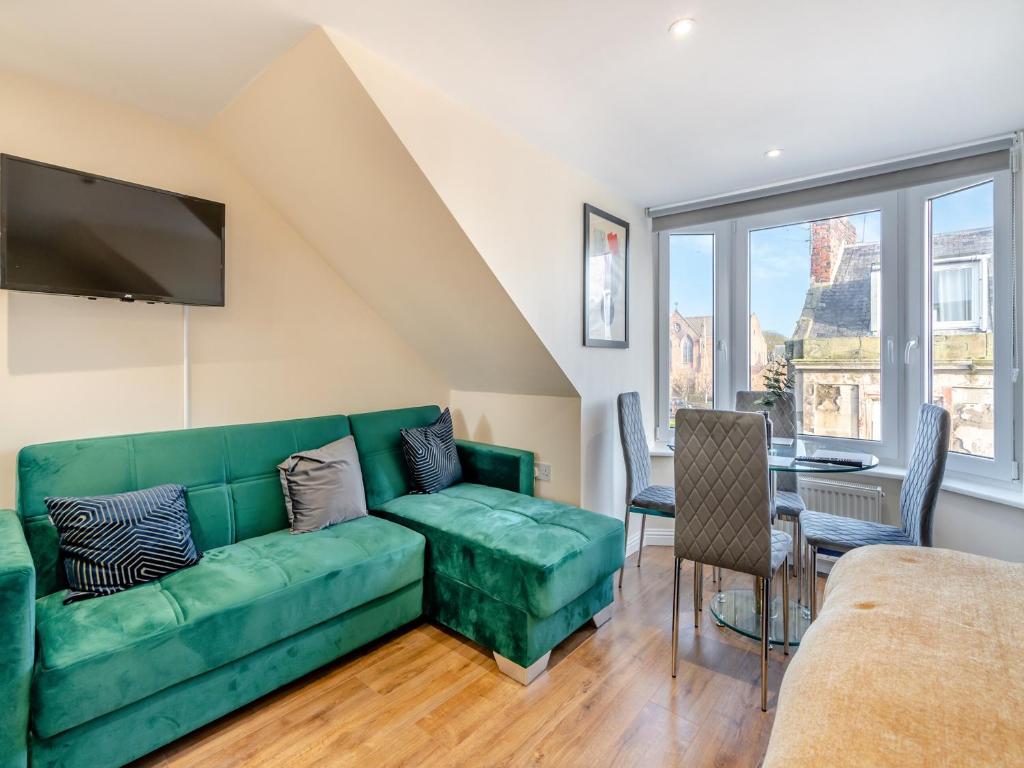 a living room with a green couch and a table at Apartment Five - Uk44289 in Arbroath