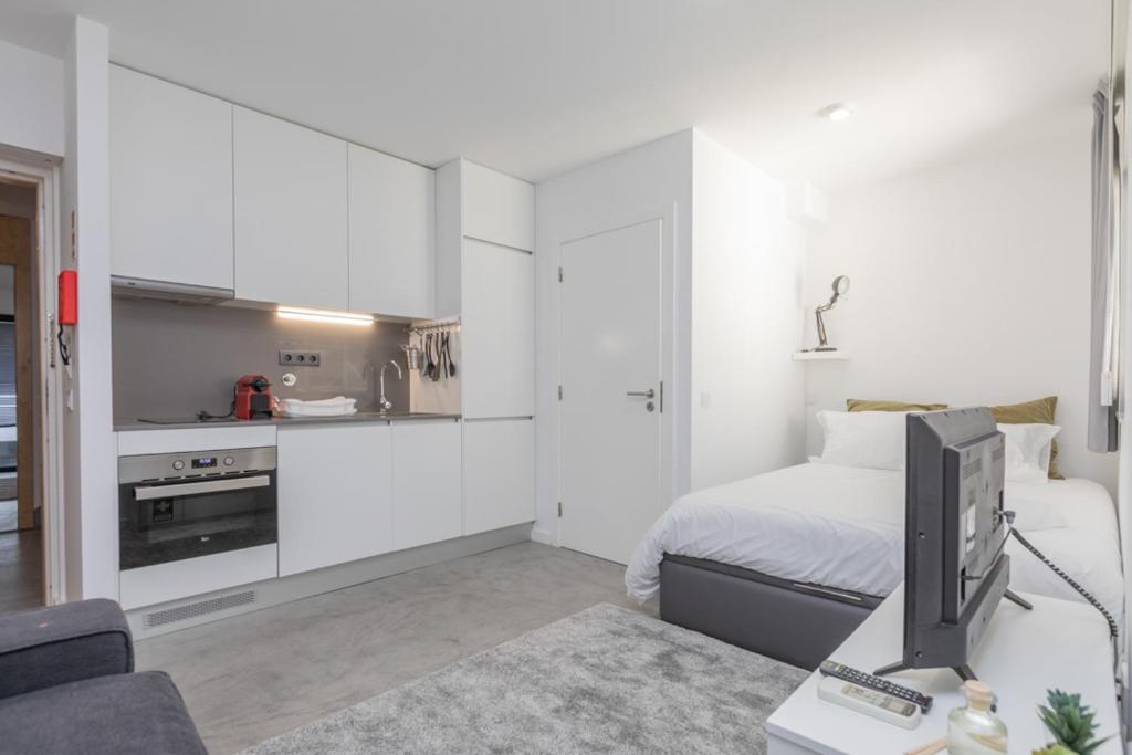 um quarto branco com uma cama e uma televisão. em AveiNest - Your Studio in Aveiro em Aveiro