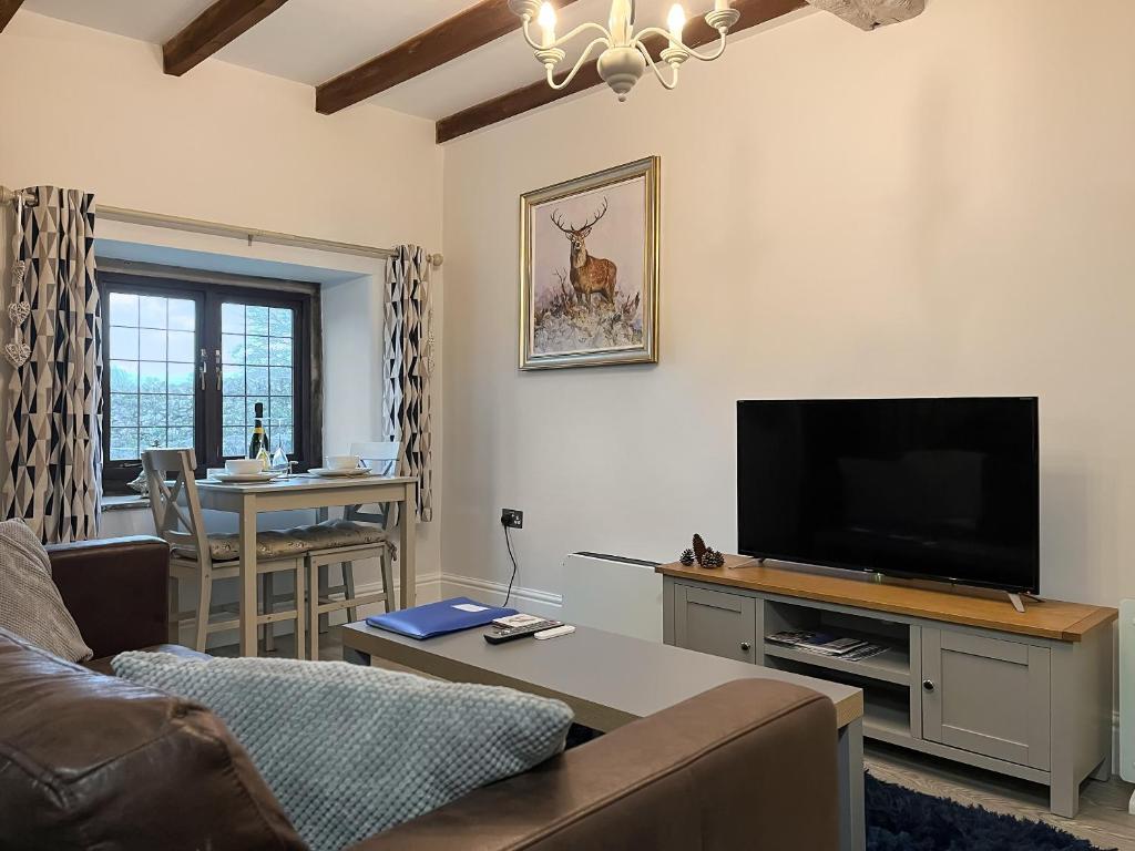 a living room with a couch and a flat screen tv at Denver Cottage - Uk46029 in Monyash