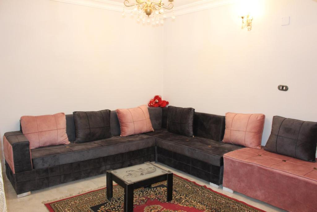 ein Wohnzimmer mit einem braunen Sofa und rosa Kissen in der Unterkunft Entire rental unit in New Cairo, Egypt in Kairo