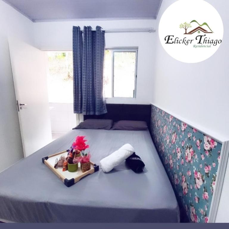 Una cama con una bandeja de flores. en Apartamento Superior, en Balneário Camboriú