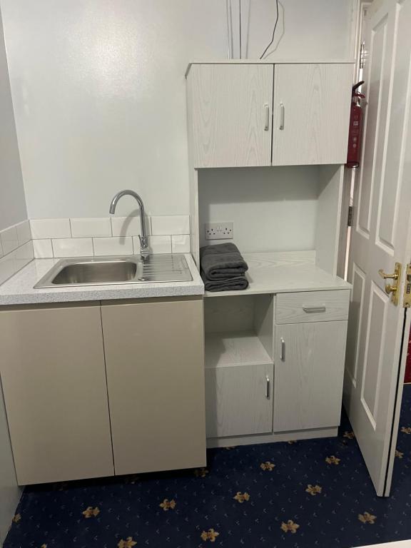 a kitchen with white cabinets and a sink at La Vera in South Norwood