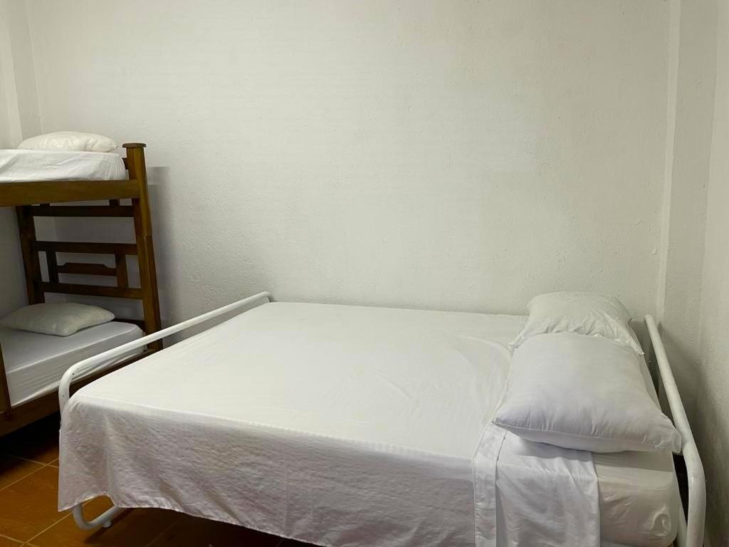 Cama blanca en una habitación con estantería en Hostal Casablanca Santa Marta, en Santa Marta