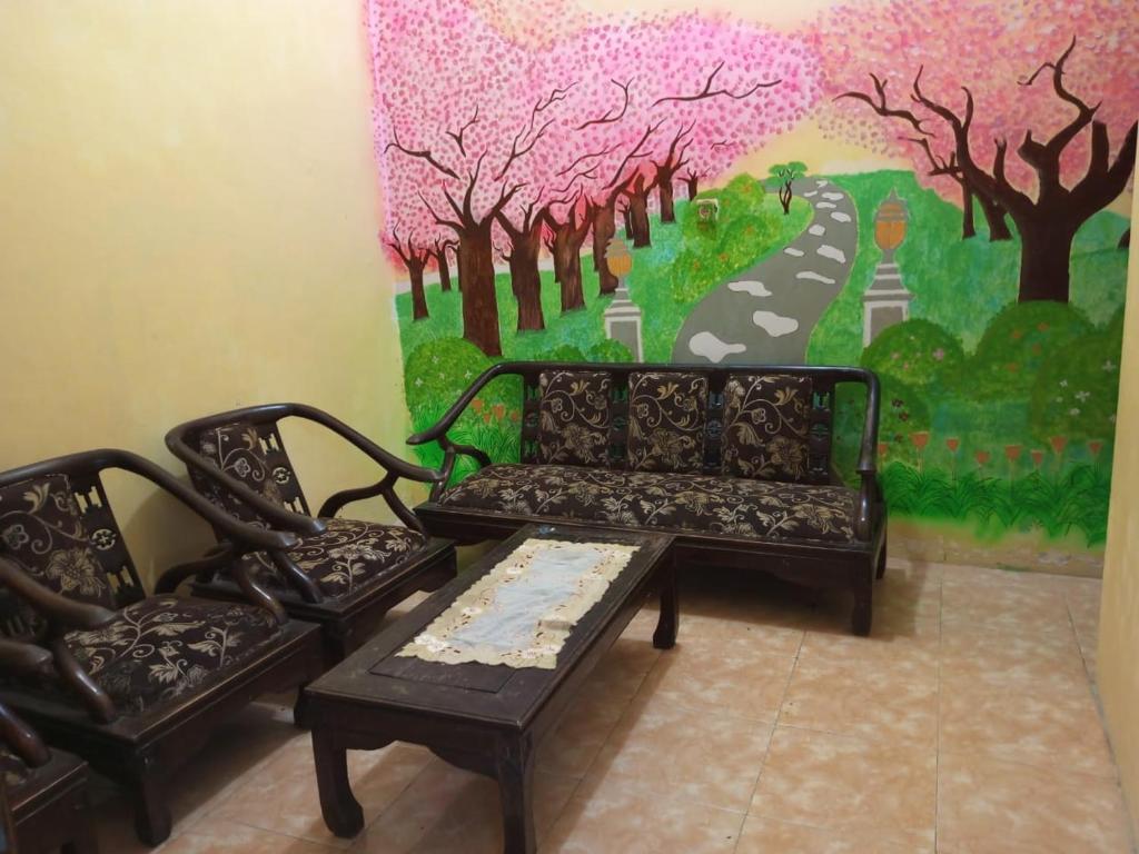 ein Wohnzimmer mit einem Sofa, 2 Stühlen und einem Gemälde in der Unterkunft Sakinah Villa Penataran in Berni