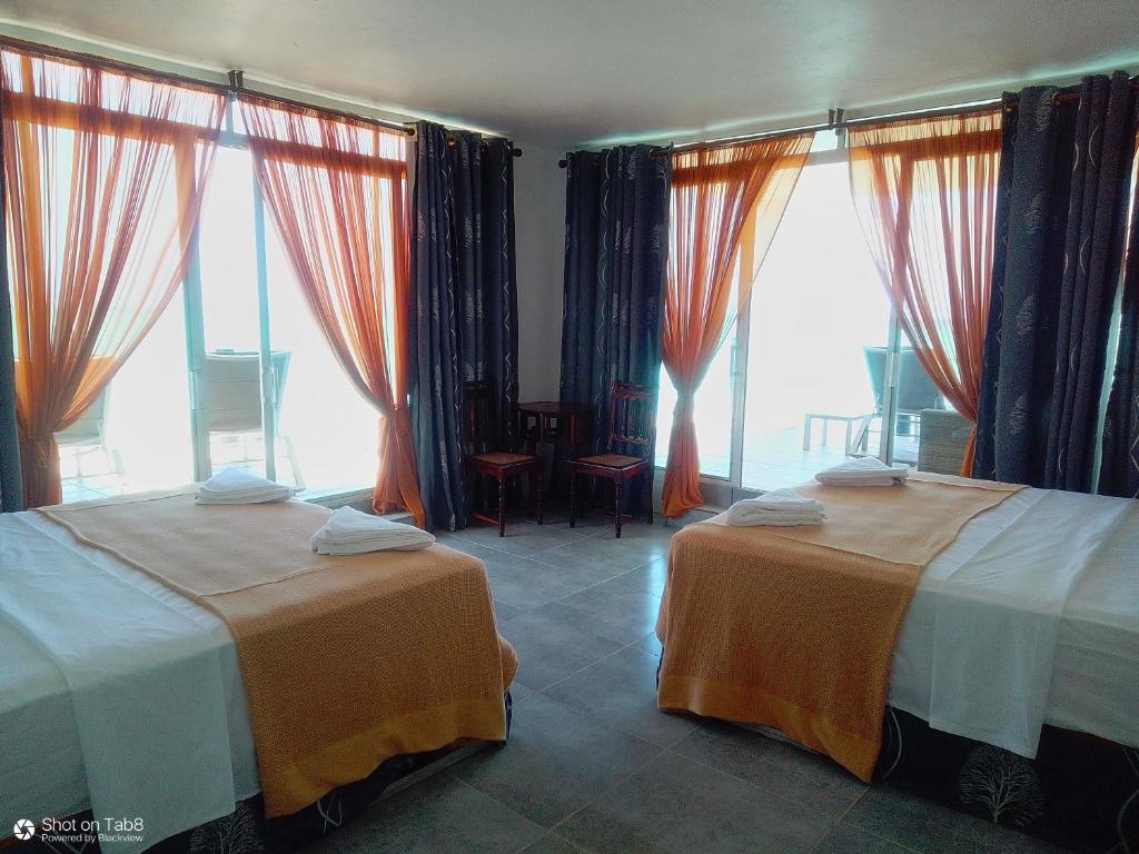 Duas camas num quarto com janelas grandes em Game Fish Lodge em Nungwi