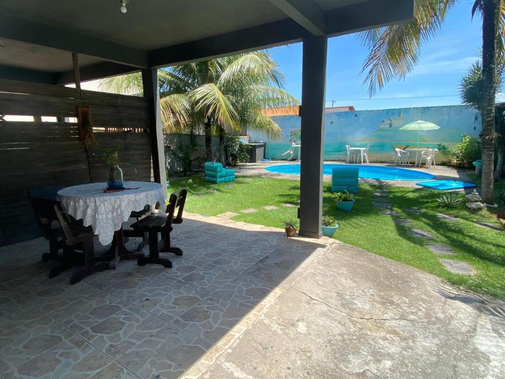 un patio con mesa, sillas y piscina en Casa de Praia LOFT 1 en Saquarema