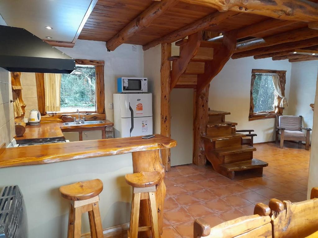 una cucina con bancone e alcuni sgabelli in legno di Cabaña El Viaje a San Carlos de Bariloche