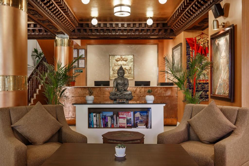 a living room with two chairs and a statue at Hotel Tibet in Kathmandu