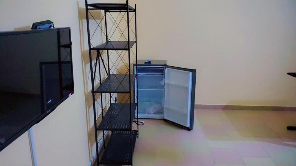 un frigorifero vuoto con scaffali in una stanza di Studio privatif spacieux en air de plage a Cotonou