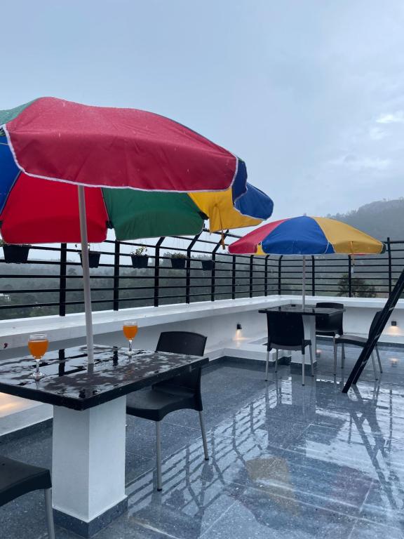 stół z dwoma kolorowymi parasolami na dachu w obiekcie Hotel Kanvinra w mieście Bandarawela