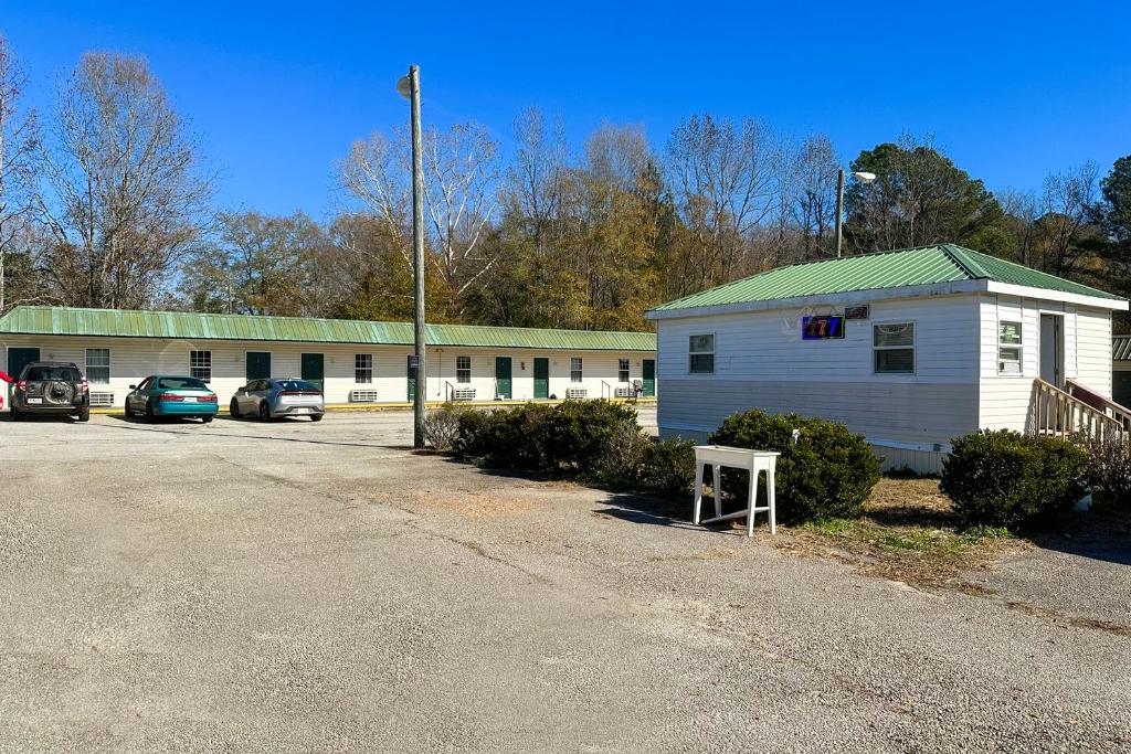 een wit gebouw met een groen dak en een parkeerplaats bij Sparta Seven Motel By OYO near Milledgeville in Sparta