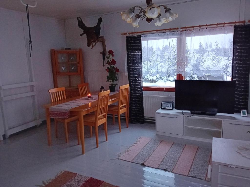 sala de estar con mesa, sillas y TV en Talo rantasaunalla en Vaala