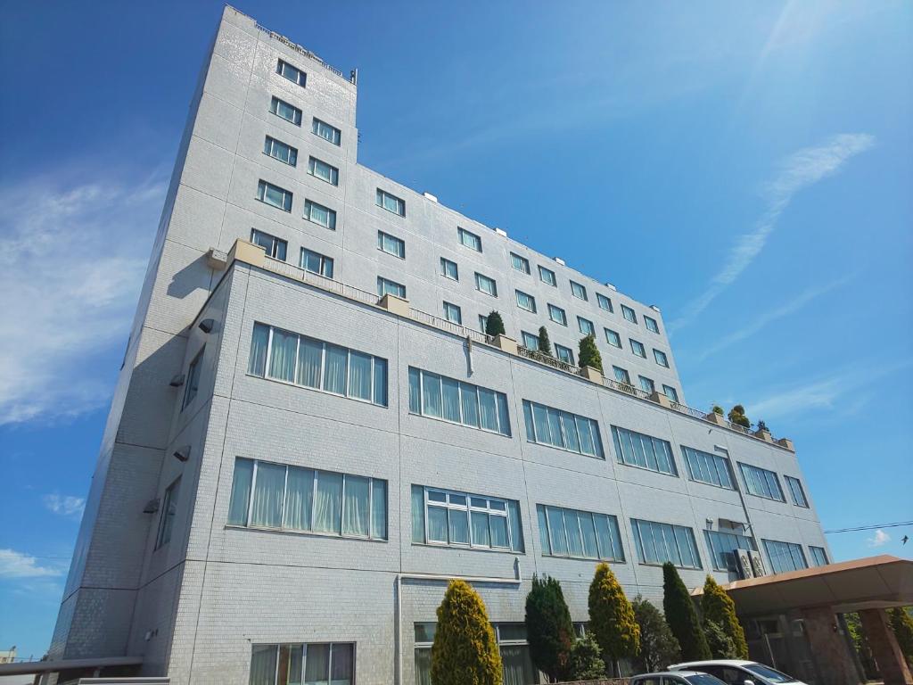 ein hohes weißes Gebäude mit Bäumen oben drauf in der Unterkunft New Grand Hotel in Shinjo