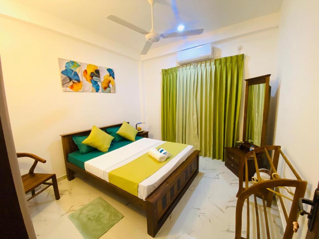 a bedroom with a bed and a green curtain at TwinsTop Villa in Minuwangoda