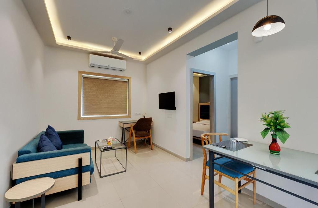 a living room with a blue couch and a table at Bliss Serviced Apartments in Gandhinagar