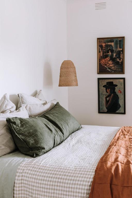 ein Schlafzimmer mit einem Bett mit grünen Kissen und einer Lampe in der Unterkunft Miss Boulevard - Stylish Art Deco Villa in Shepparton