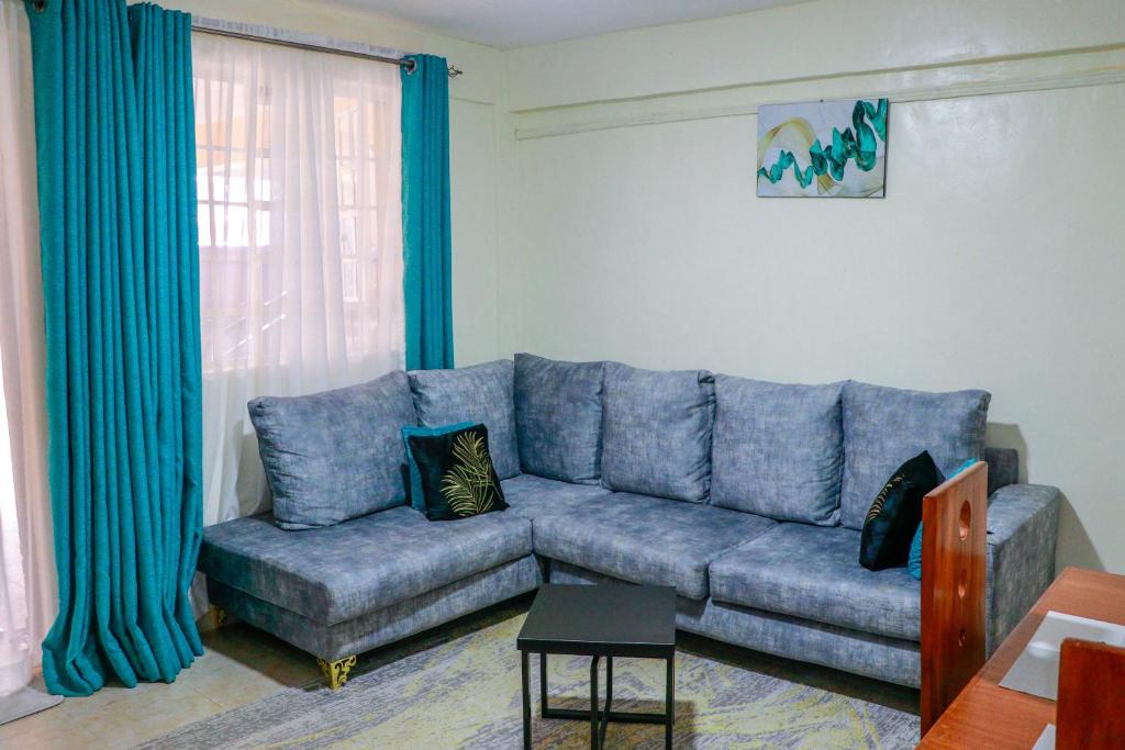 ein blaues Sofa im Wohnzimmer mit blauen Vorhängen in der Unterkunft J&jluxury homes in Kericho