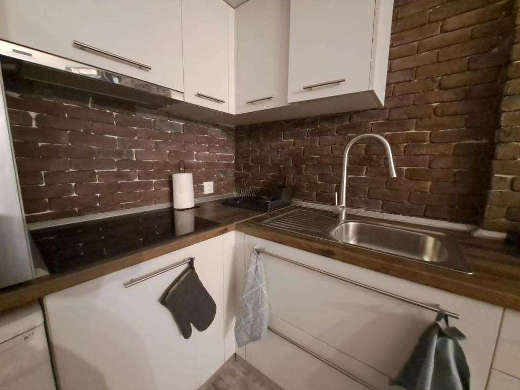 een keuken met witte kasten, een wastafel en een bakstenen muur bij Ellis Apartments in Thessaloniki