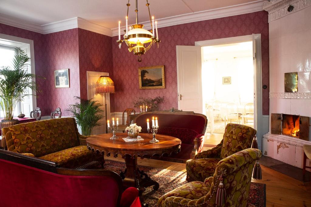 - un salon avec une table, des chaises et une cheminée dans l'établissement Långbro Gård i Mölnbo, à Mölnbo
