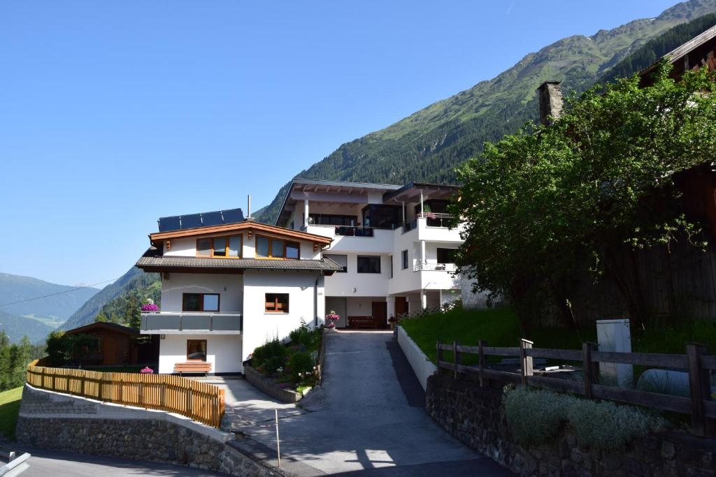 ein großes weißes Gebäude mit Bergen im Hintergrund in der Unterkunft Apart Belvita in Sankt Leonhard im Pitztal