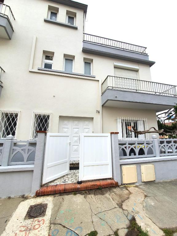une maison blanche avec deux portes devant elle dans l'établissement LA CASEBLANQUE Maison près de la plage : Wifi-Clim-Barbecue, à Canet