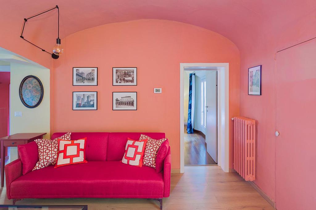 - un canapé rouge dans une chambre avec un mur orange dans l'établissement Lussuoso Appartamento nel Cuore del Centro Storico, à Bologne