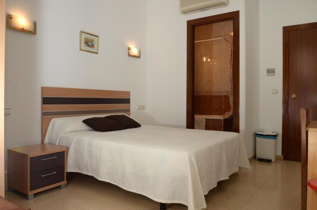 a bedroom with a large bed and a night stand at Pension Canadiense in Barcelona