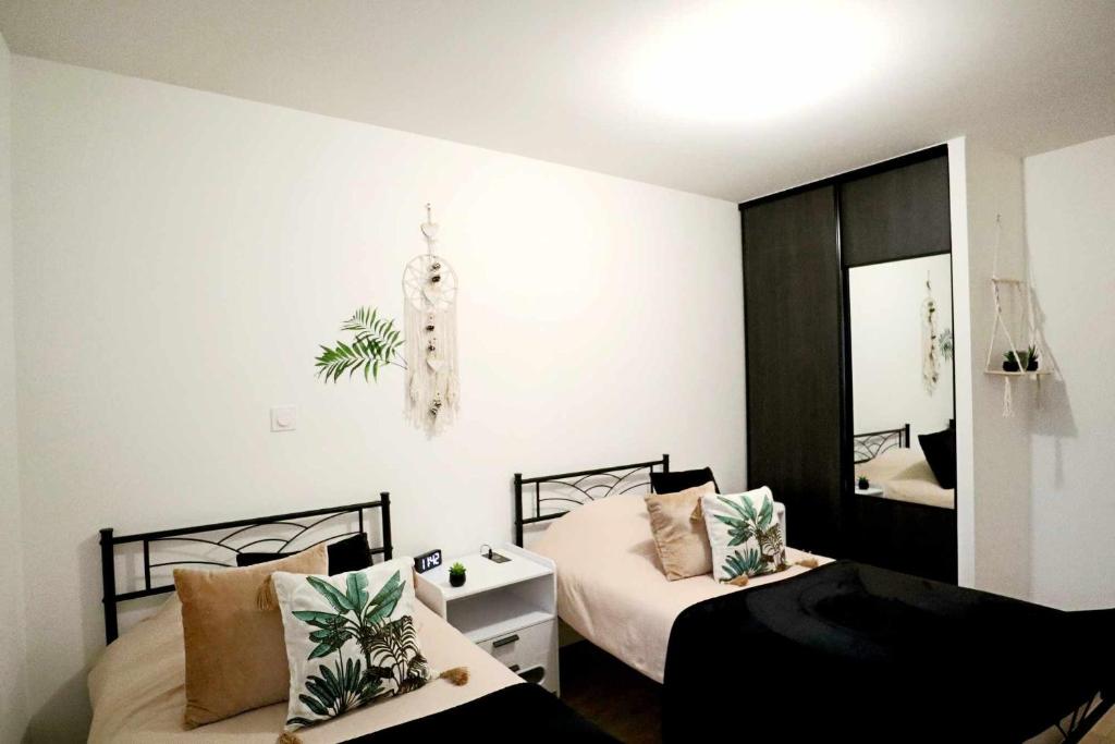 a bedroom with two beds and a mirror at Appartement Le Moderne Idéal pour Couples et Professionnels in Ornans