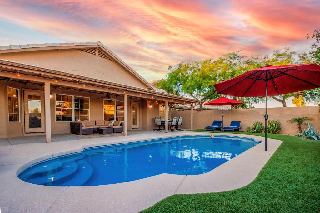 uma casa com piscina e guarda-sol em Luxe Phoenix Getaway (heated pool, mountain view) em Phoenix