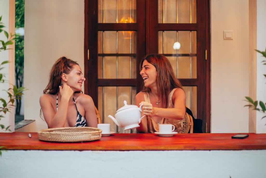 米瑞莎的住宿－Prasith’s Place，两个女人坐在桌子边,茶壶