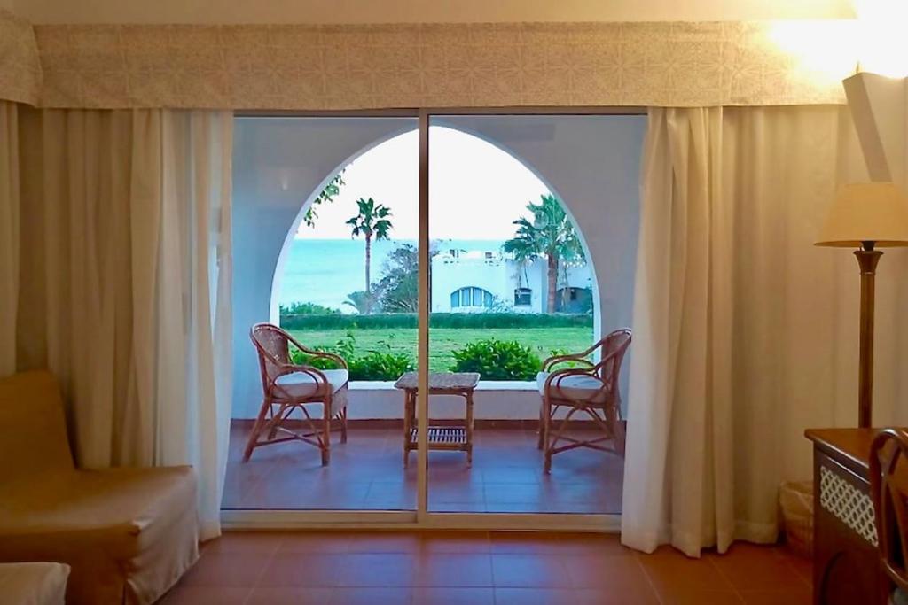 Habitación con ventana grande con mesa y sillas. en Appartamento trilocale con vista mare Domina Coral Bay R23121, en Sharm El Sheikh