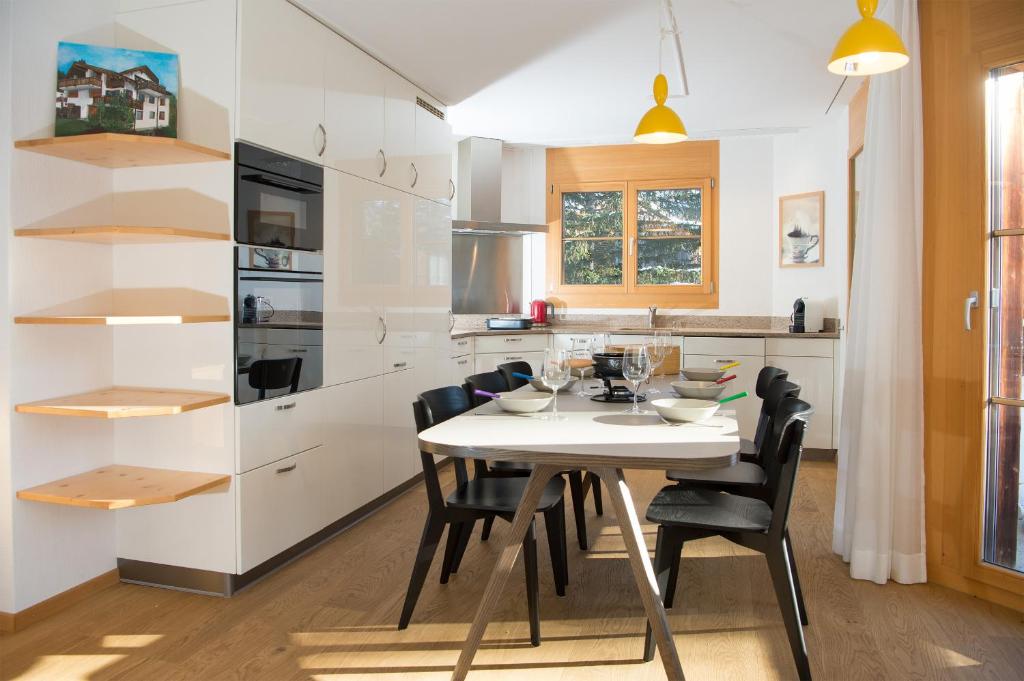 a kitchen with a white table and black chairs at Holiday flat for 6 people Sot Valos Lenzerheide centre in Lenzerheide