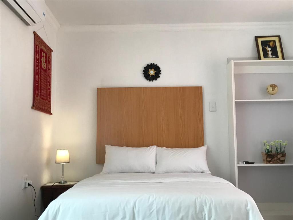 a bedroom with a white bed with a wooden headboard at The Affectionate One in Louis Trichardt