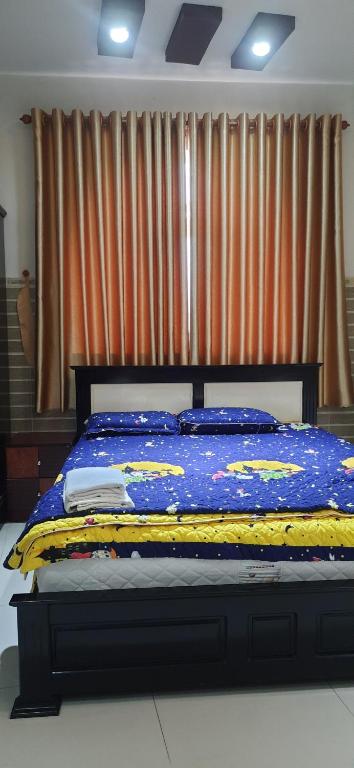 a bed with a blue and yellow quilt on it at Khách Sạn Xuân Nguyên - Nam Sài Gòn in Bình Chánh