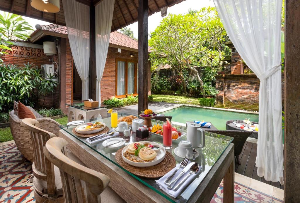 einen Tisch mit Essen neben einem Pool in der Unterkunft Ubud Raya Villa in Ubud
