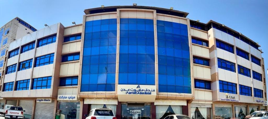 un gran edificio con ventanas azules en una ciudad en فندق ماريوت عدن السياحي Marriott Aden Hotel, en Khawr Maksar